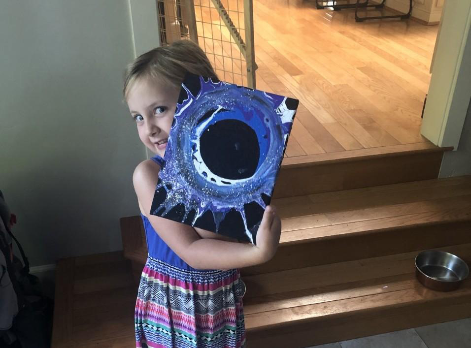 Preschool student Evelyn poses with artwork she made at home as part of the Preschool Learning Lab.