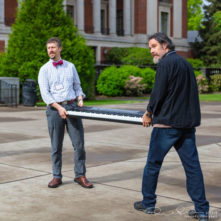 Dr. Blau and colleague walking with a musical keyboard