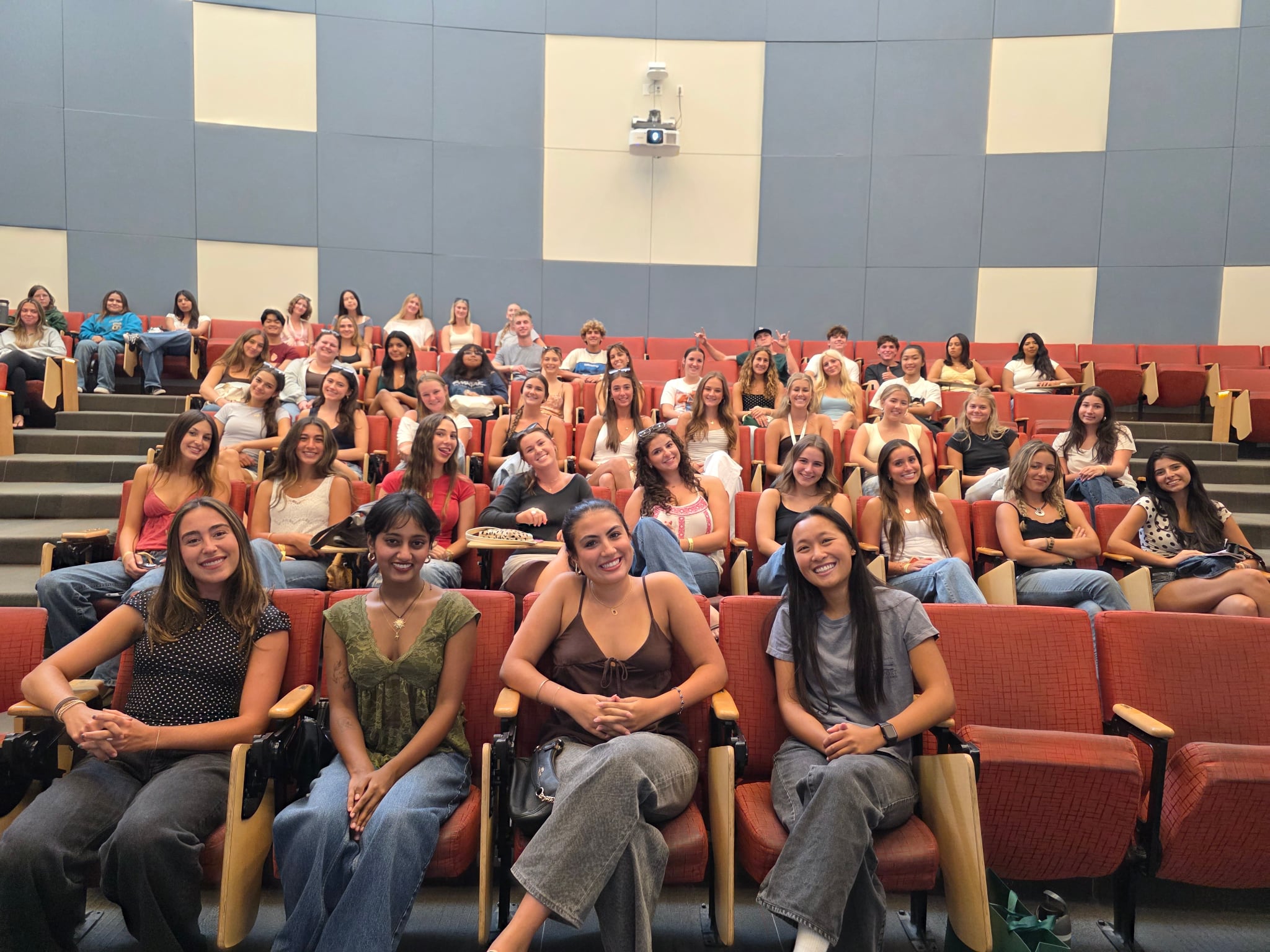 New COMS majors sitting in an auditorium smiling