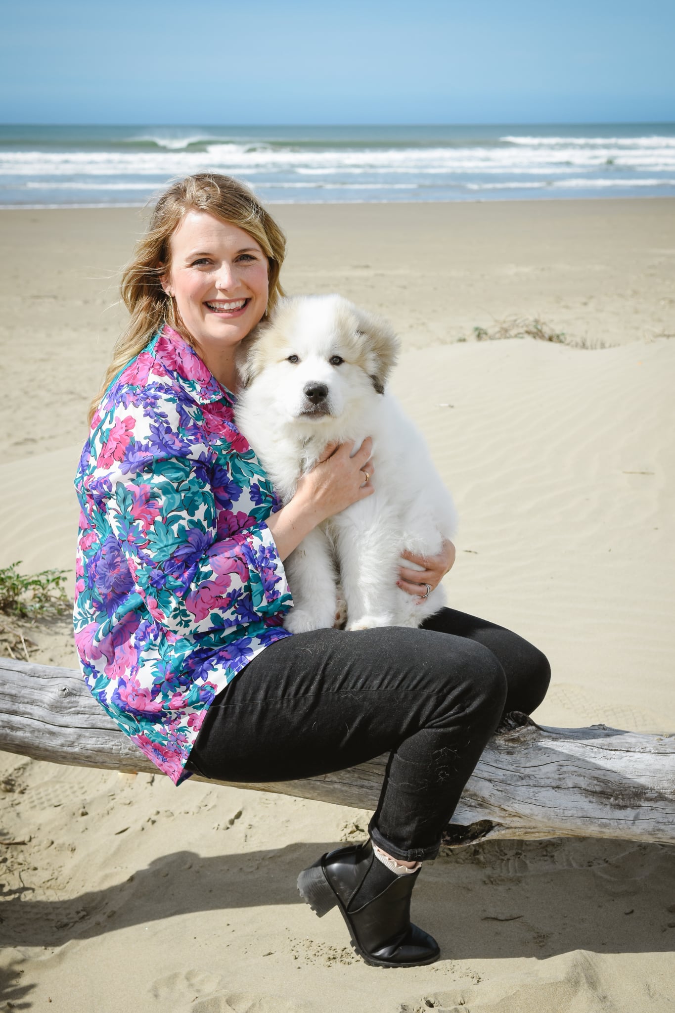 Dr. Nelson smiling with her white dog in front of the ocean