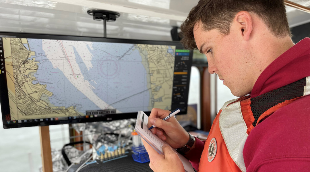 Oceanography student takes notes in front of a map