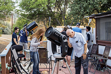 Students, mentors look through at telescope from an outdoor deck