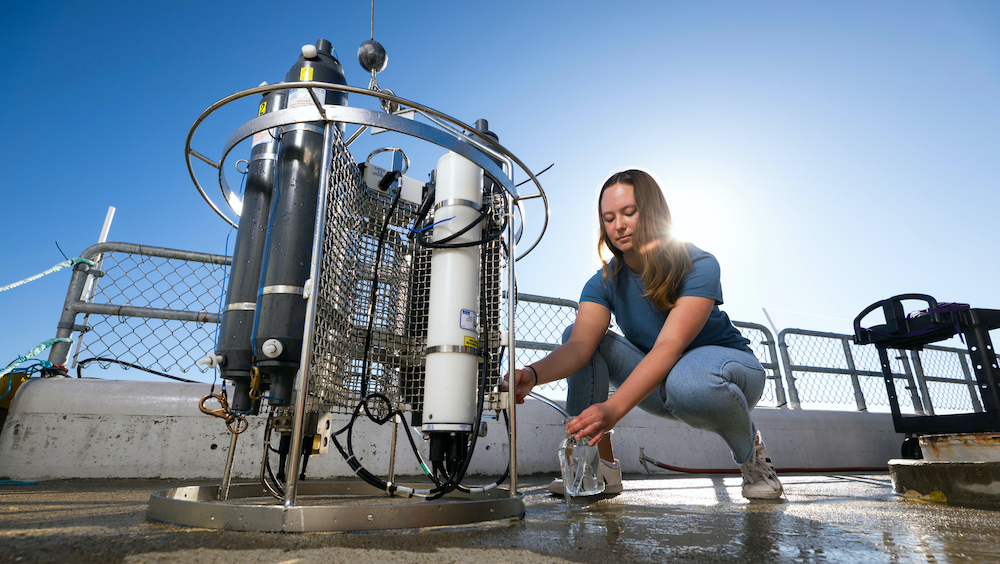 Student testing water pH levels using a large machine outside.