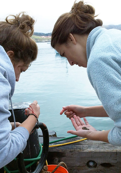 Two girls examining a rock on a boat.