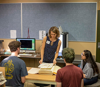 Staff and students examine dried plants in the university herbarium