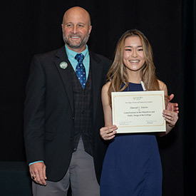 Hannah Simons holds her certificate and stands with Dean Wendt