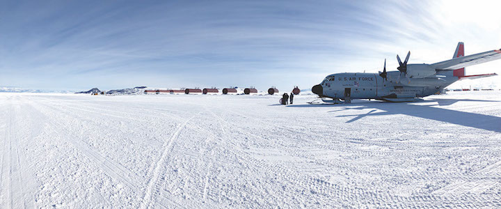 A giant plane sits in an open snow field, ready for take off. 