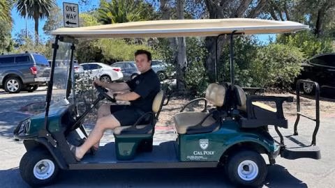 tram-service DRC Tram driver sits in driver's seat of golf cart while looking towards camera