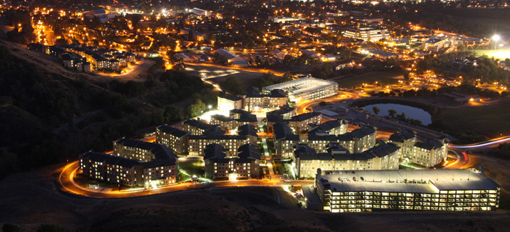 Aerial view of Cal Poly lit up at night, looking from over Poly Canyon