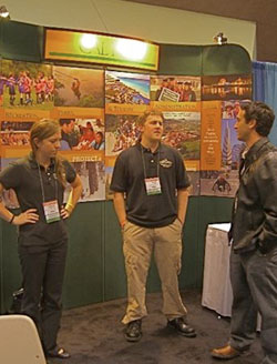 Male and female student talking to male alumni at RPTA booth at conference