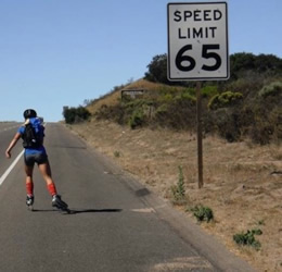 Kacie skating on a highway next to a 65mph sign