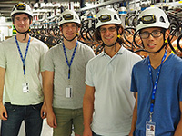 Professor and three students wearing hardhats and standing in an equipment room