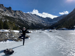 Julia Maddalena standing on one leg on a frozen river in the mountains