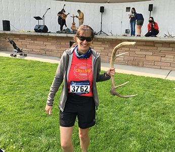 Beth Chance wearing a running outfit and race number and holding deer antlers