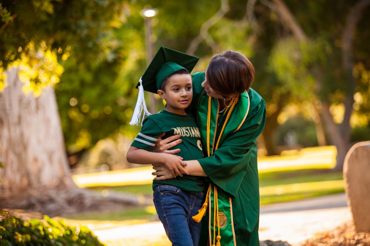 Cal Poly student in cap and gown with son